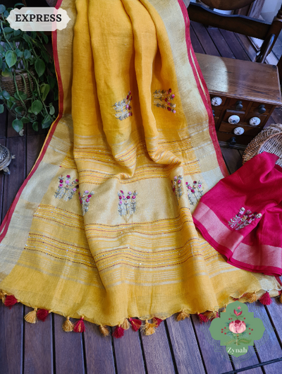 Bright yellow pure linen saree with a sparkling zari border and delicate french-knot embroidered butis. The pallu is adorned with intricate kantha work designs.