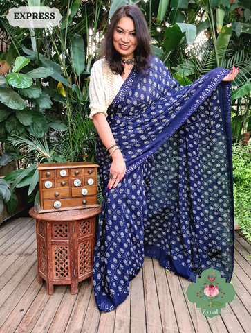 A blue crepe silk saree featuring bandhani inspired prints and intricate mirror work on the scalloped borders.