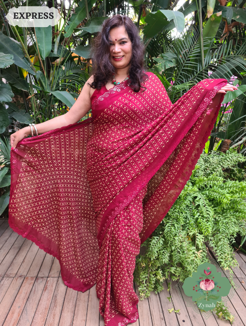 A deep maroon crepe silk saree decorated with bandhani inspired prints and adorned with mirrored embellishments on the scalloped borders.